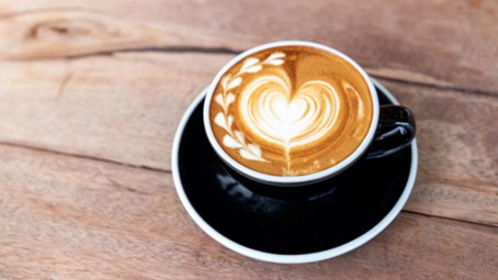 Cappuccino cup with heart-shaped latte art and little hearts