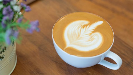Tasse de capuccino avec latte art en forme de coeur et feuille